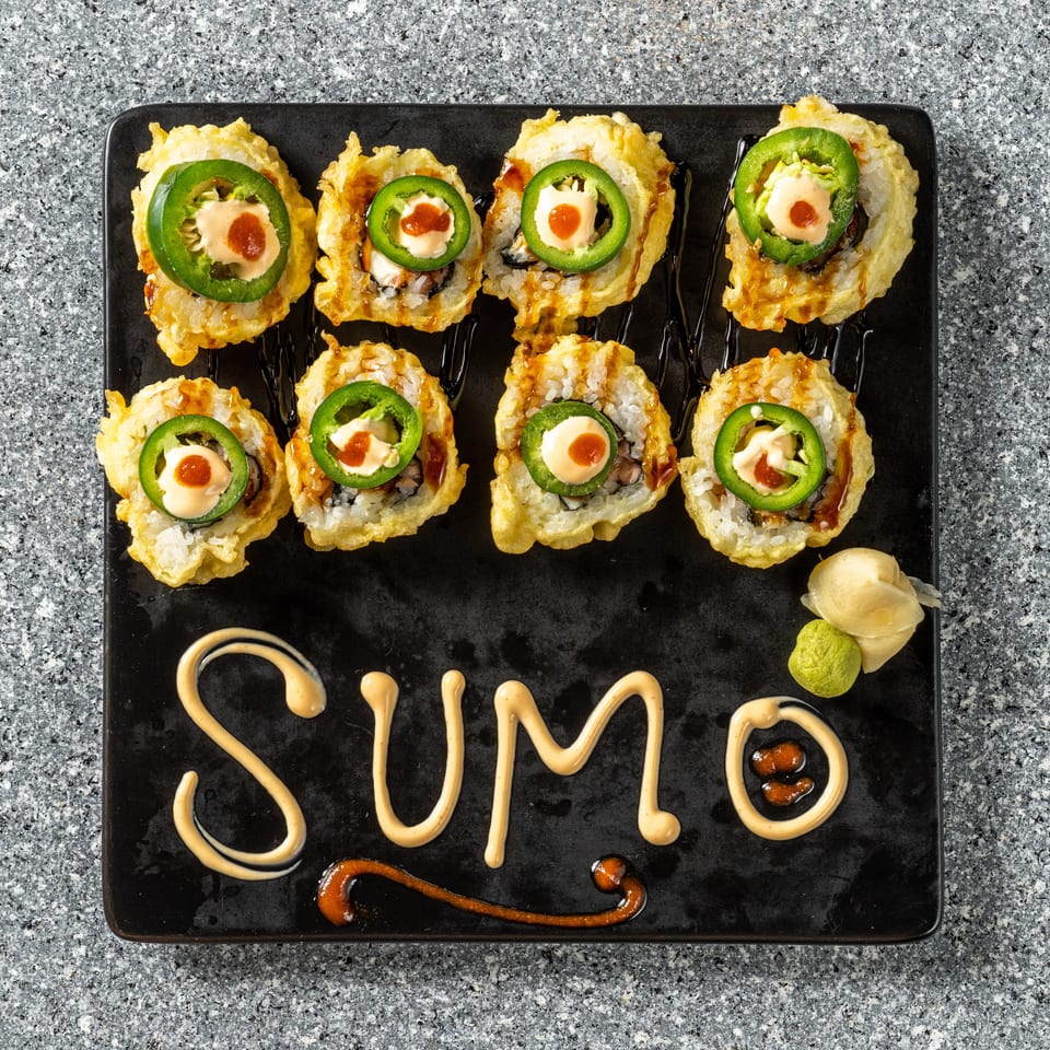 Eight fried sushi rolls topped with jalapeño, sauce, and a red dot, with "SUMO" written in sauce.