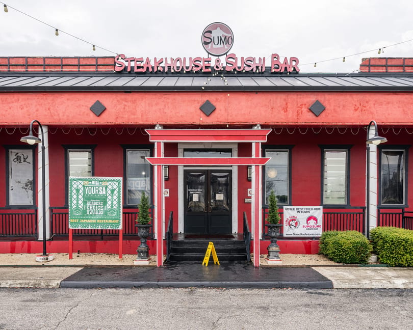 The red exterior of Sumo Steakhouse & Sushi Bar, with a red torii gate entrance and award signs.