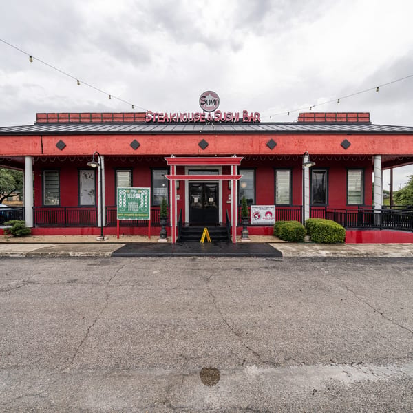 Exterior of Sumo Steakhouse & Sushi Bar, a red building with a black roof and a red torii gate entrance.