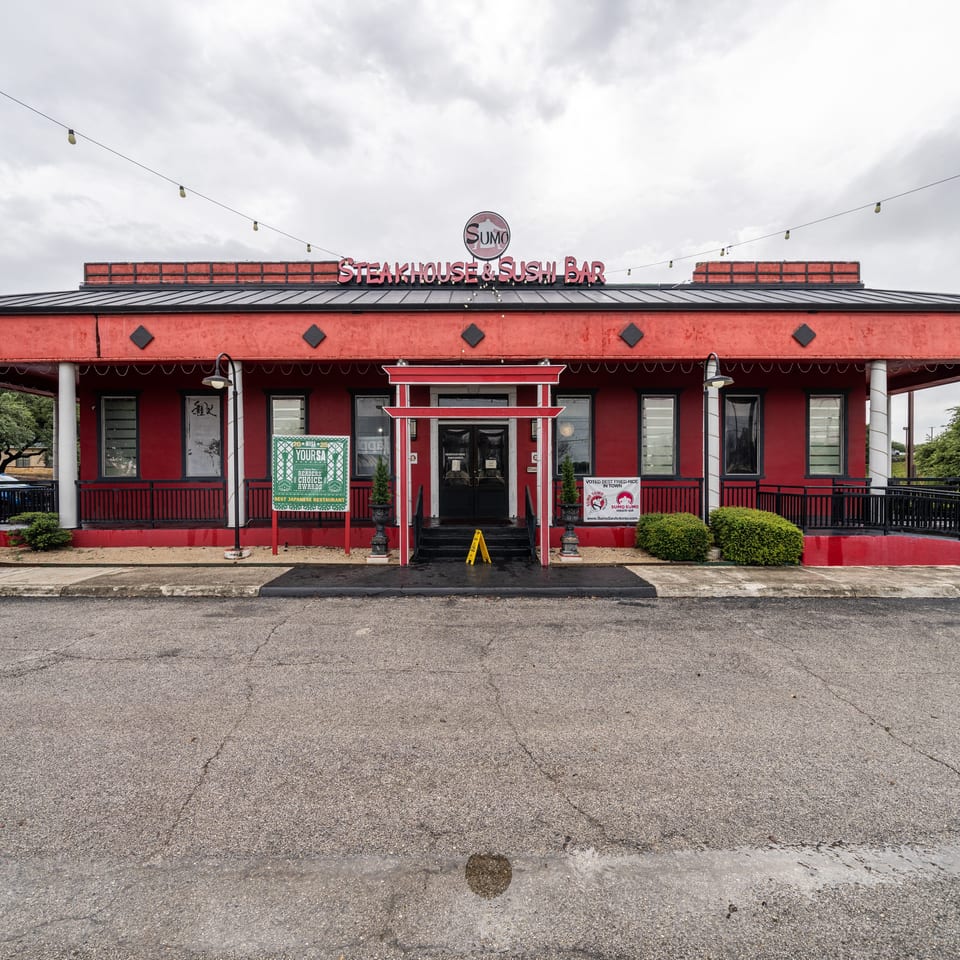 Exterior of Sumo Steakhouse & Sushi Bar, a red building with a black roof and a red torii gate entrance.