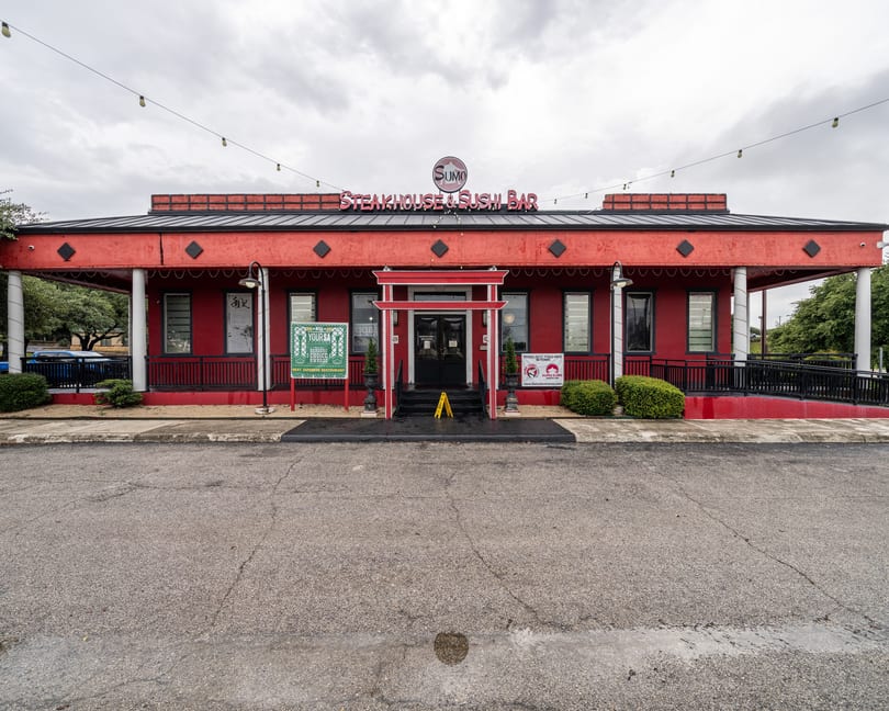 Exterior of Sumo Steakhouse & Sushi Bar, a red building with a black roof and a red torii gate entrance.