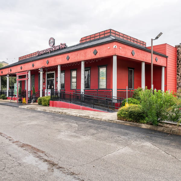 Exterior of Sumo Steakhouse & Sushi Bar, a red building with white pillars and a black roof.