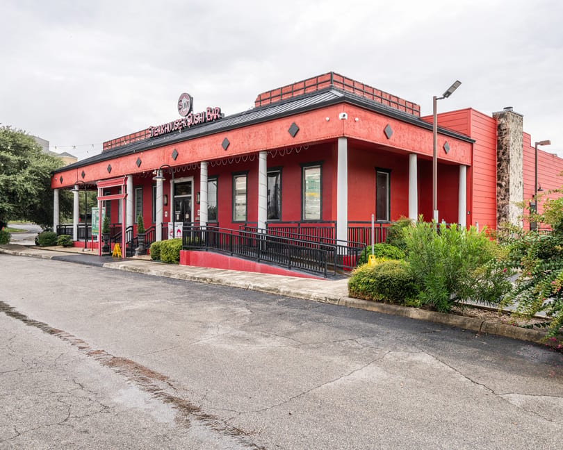 Exterior of Sumo Steakhouse & Sushi Bar, a red building with white pillars and a black roof.